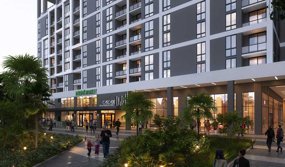 A modern multi-story apartment building in Sunny Isles Beach features large windows and shops at ground level, including NABAR MARKET and CASCADE. People stroll along a landscaped pathway lined with palm trees and greenery.